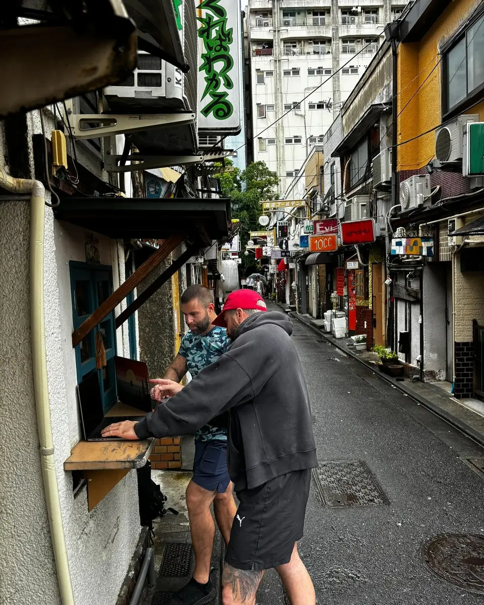 Spencer Beaudreault and Jason Skeldon working on a laptop in an alley in Osaka, Japan